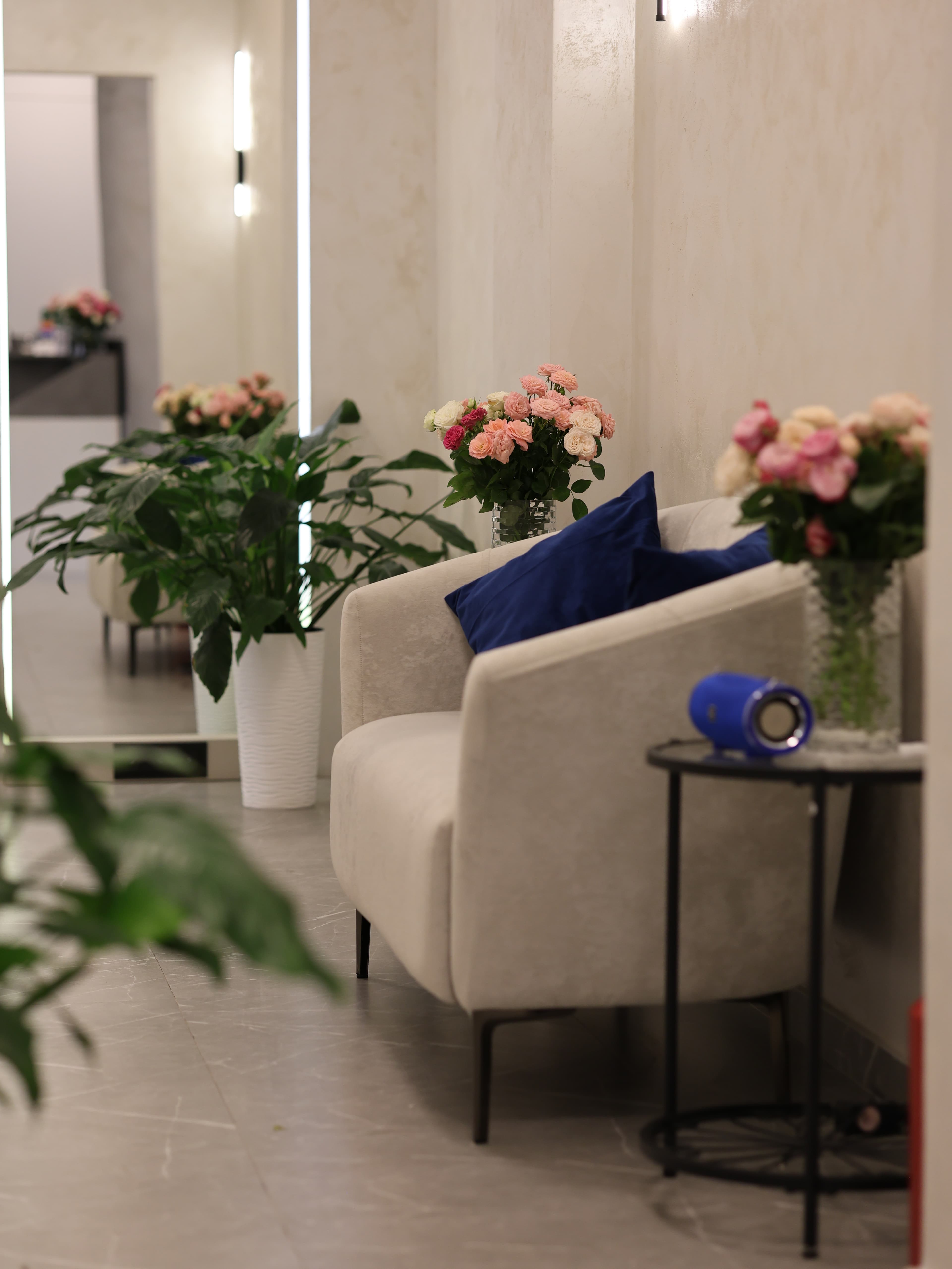 AURA waiting area with a cream sofa, flowers, and navy cushions